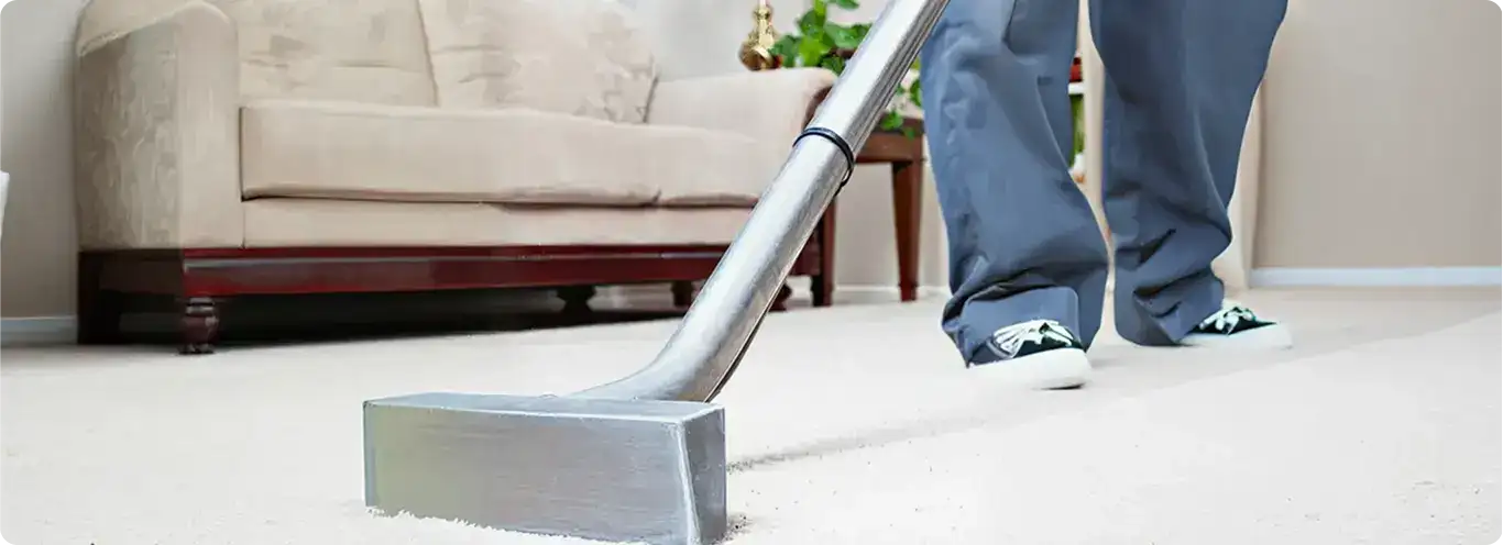 Carpet cleaning technician using a hot-water extraction wand on a light-colored carpet in a living room, {city}, {state}.